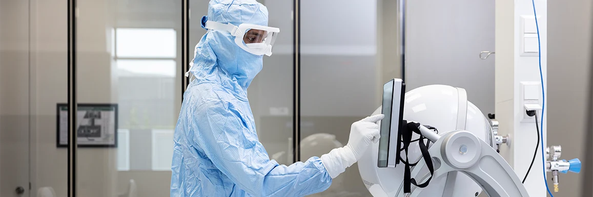 A person in protective clothing typing on a touchscreen (photo)